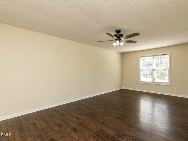 an empty room with wooden floor and ceiling fan