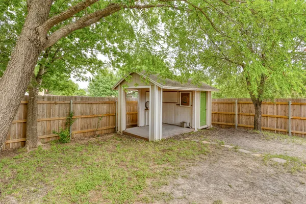 a view of a small house with a small yard and a large tree