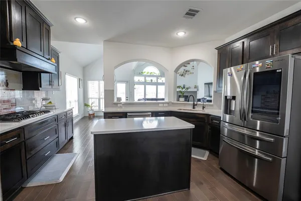 a kitchen with stainless steel appliances granite countertop a sink a stove and a refrigerator