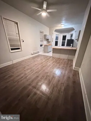 a view of a livingroom with wooden floor and kitchen space