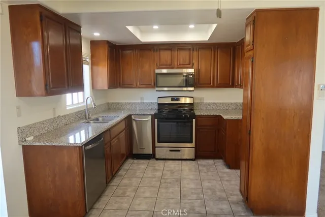 a kitchen with stainless steel appliances granite countertop a refrigerator a stove a sink and a microwave