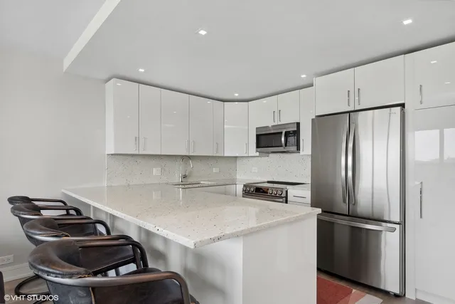 a kitchen with a sink a refrigerator and white cabinets