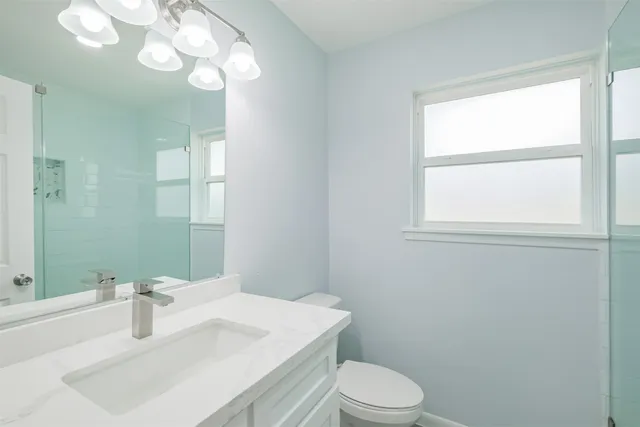 a bathroom with a sink vanity granite toilet and a mirror