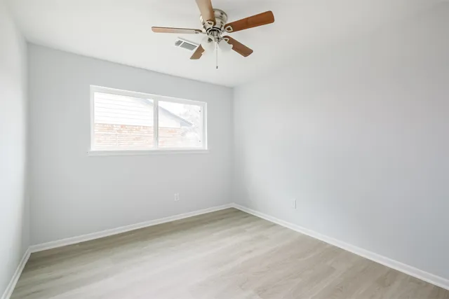an empty room with a window and a fan