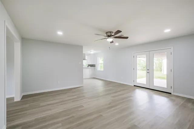 a view of an empty room with a window and wooden floor