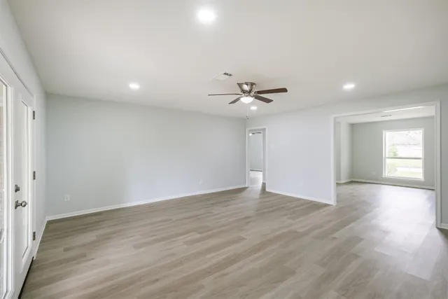 a view of an empty room with a window and wooden floor