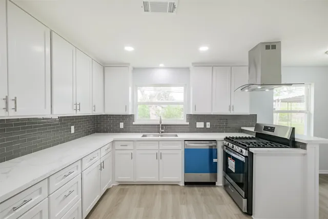 a kitchen with a sink stove top oven and cabinets