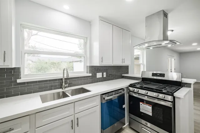 a kitchen with stainless steel appliances granite countertop a sink a stove cabinets and a window