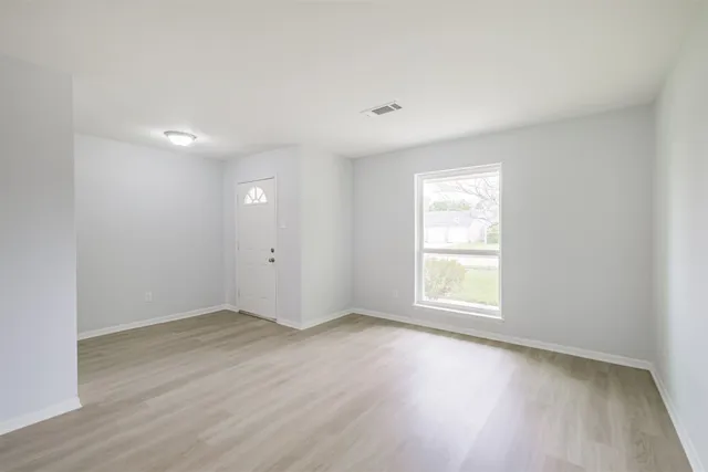 an empty room with wooden floor and window