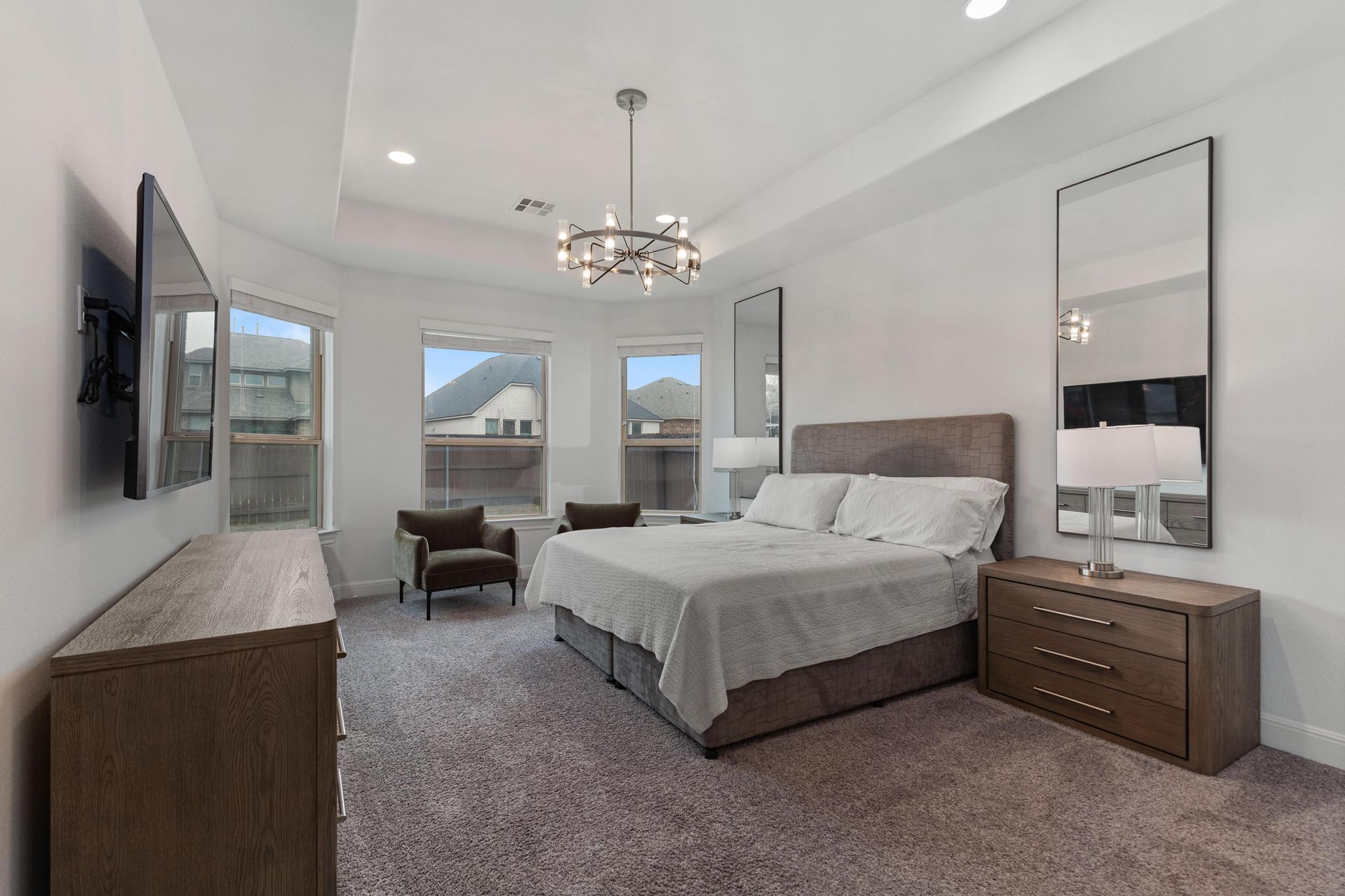 3028 Silvergrass Cove Leander, TX 78641 - Photo 16 of 38 Bedroom with a raised ceiling, dark colored carpet, and hanging lights