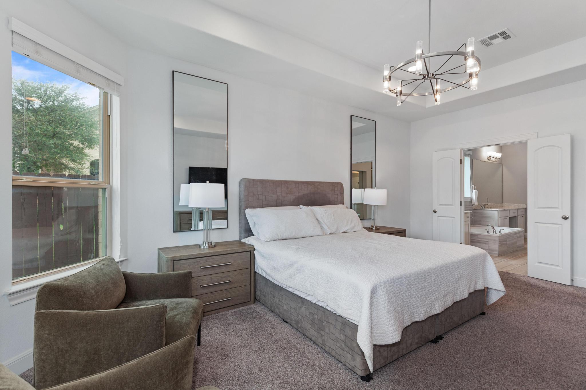 3028 Silvergrass Cove Leander, TX 78641 - Photo 17 of 38 Carpeted bedroom with a chandelier, a tray ceiling, and ensuite bath