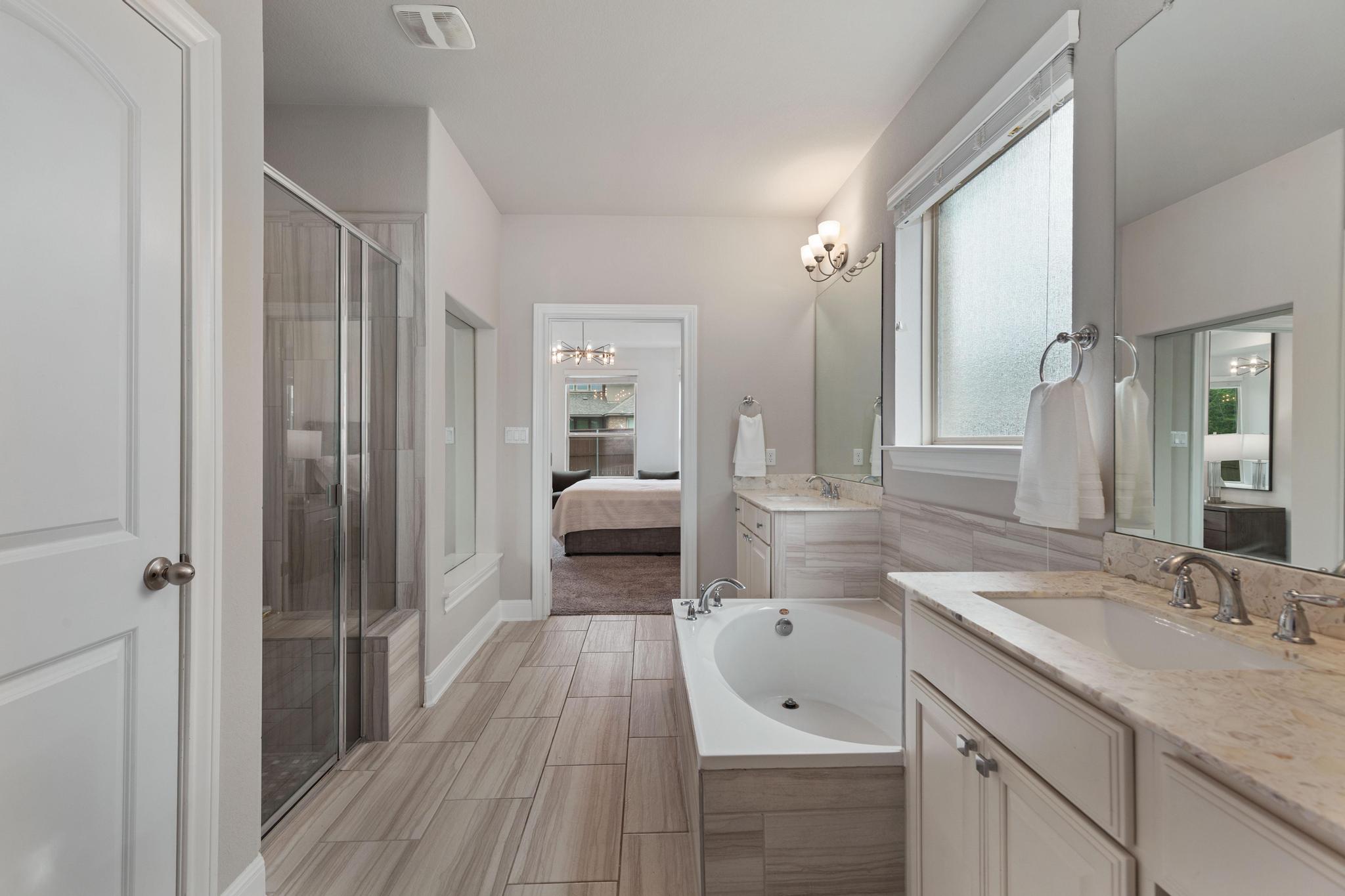 3028 Silvergrass Cove Leander, TX 78641 - Photo 18 of 38 Bathroom featuring connected bathroom, a garden tub, two vanities, and a stall shower