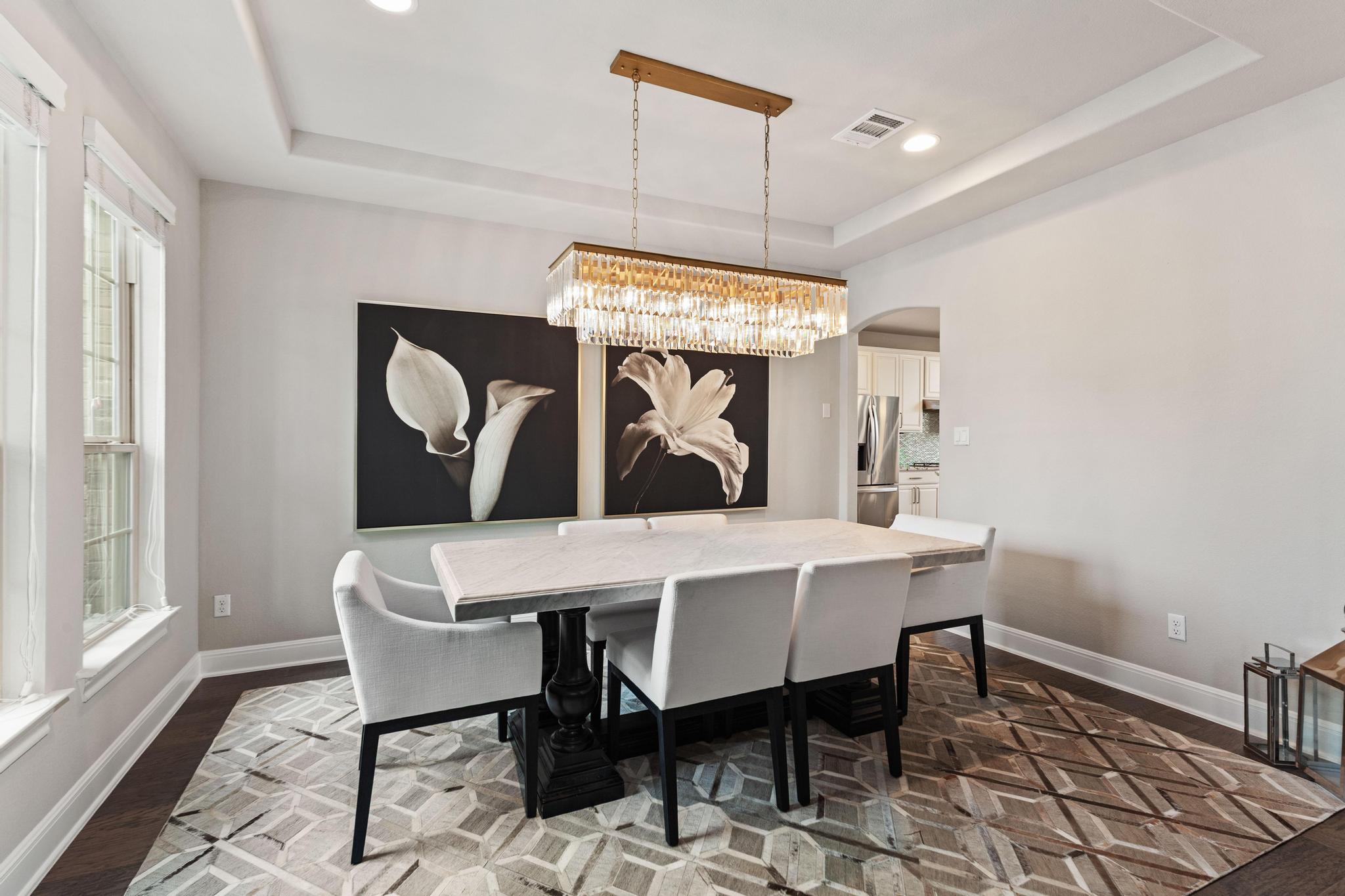 3028 Silvergrass Cove Leander, TX 78641 - Photo 3 of 38 Dining space featuring a raised ceiling, arched walkways, hanging lights, and dark wood-type flooring