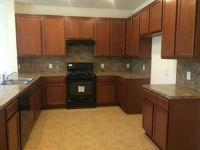 a kitchen with stainless steel appliances granite countertop a stove a sink and a microwave