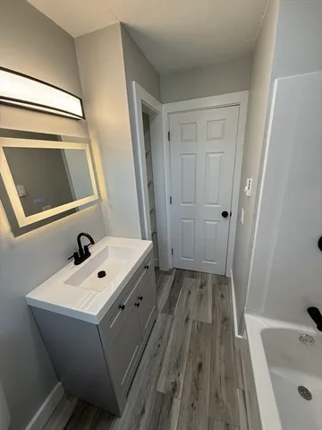 a bathroom with a tub sink and mirror