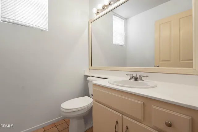 a bathroom with a granite countertop toilet sink mirror and vanity
