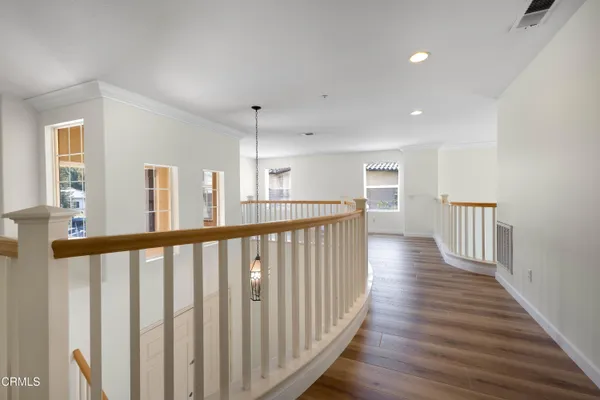 a view of a hallway with wooden floor and windows