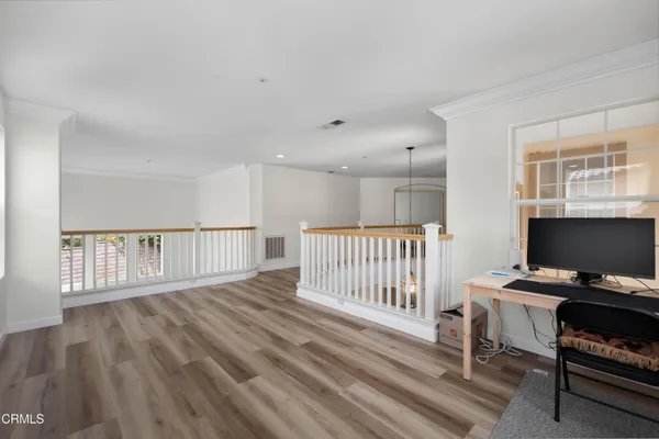a view of a workspace with wooden floor and a window