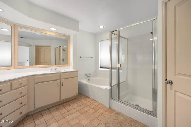 a spacious bathroom with a shower a sink and a mirror