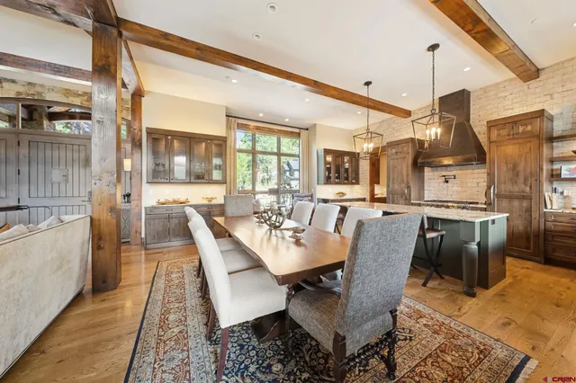 a dining room with stainless steel appliances kitchen island granite countertop a table chairs and a rug
