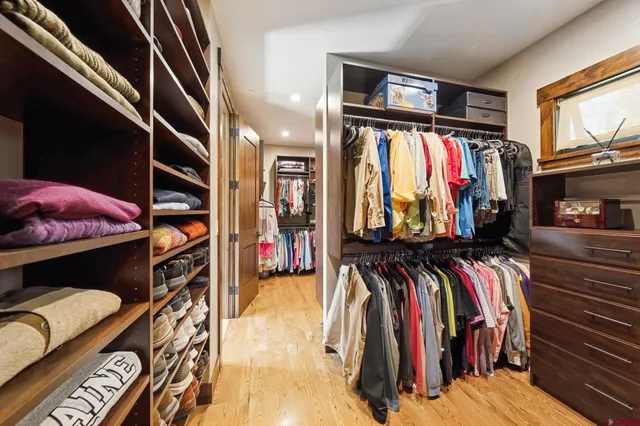 a view of walk in closet with clothes and shoes