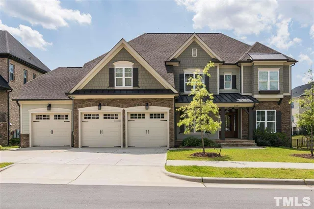 a front view of a house with a garden and trees