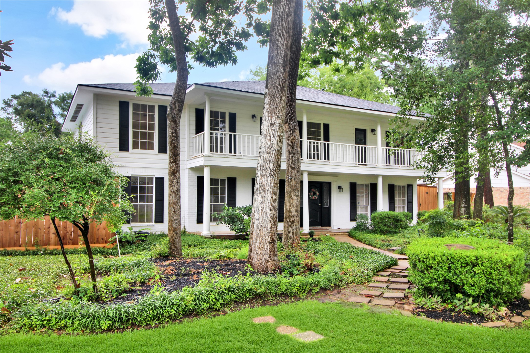 a front view of a house with a garden and trees