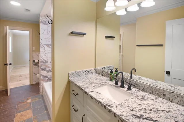 a bathroom with a granite countertop sink a mirror and shower