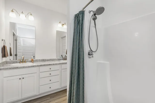 a bathroom with a granite countertop sink two mirror and a shower