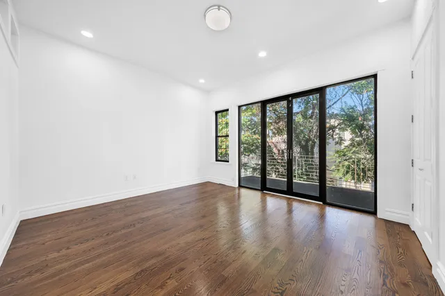 a view of an empty room with wooden floor and a large window