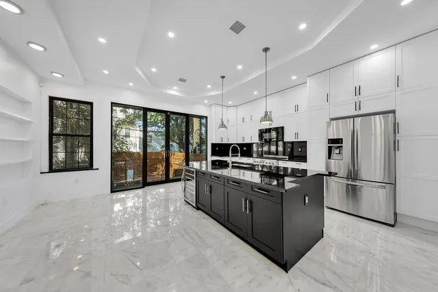 a kitchen with stainless steel appliances kitchen island granite countertop a refrigerator and a stove top oven