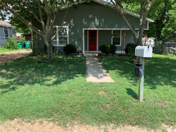 a front view of a house with garden and trees