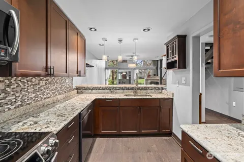 a kitchen with kitchen island granite countertop a sink stove and refrigerator