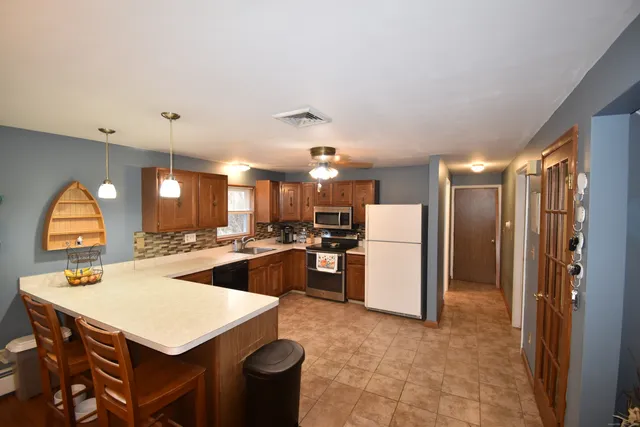 a kitchen with a refrigerator a sink dishwasher with a dining table and chairs