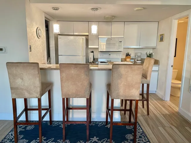 a living room with stainless steel appliances furniture a dining table and kitchen view