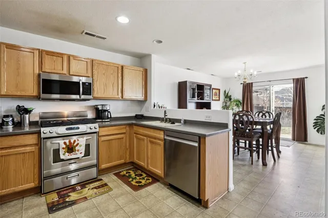 a kitchen with stainless steel appliances granite countertop a stove top oven a sink a dining table and chairs with wooden floor