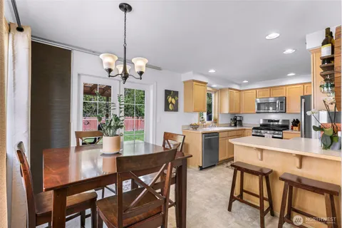 a dining room with stainless steel appliances kitchen island granite countertop a dining table chairs and a refrigerator