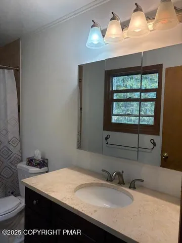 a bathroom with a granite countertop sink a toilet and a mirror