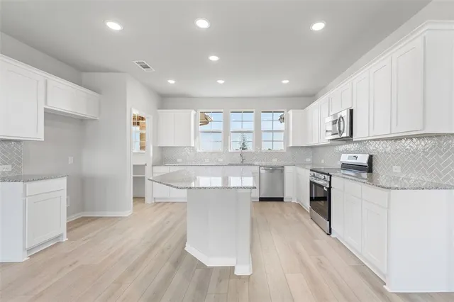 a large kitchen with kitchen island a sink a center island stainless steel appliances and a counter top space