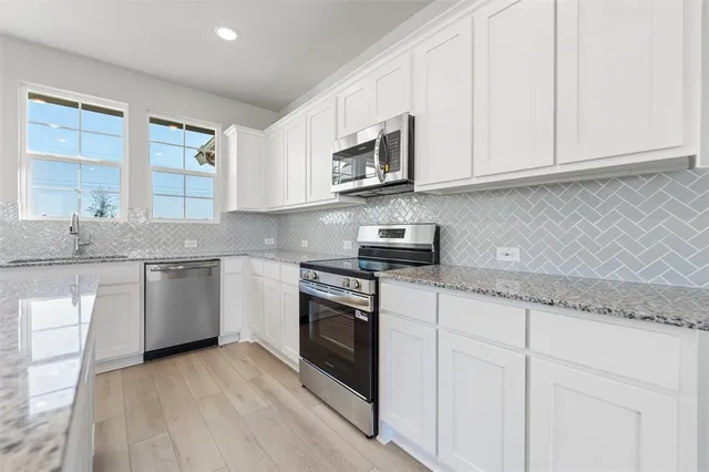a kitchen with stainless steel appliances granite countertop a sink and a stove