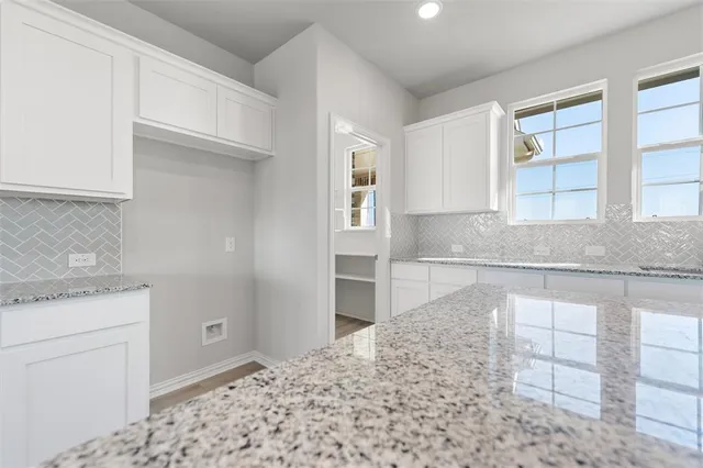 a kitchen with granite countertop a sink and white cabinets