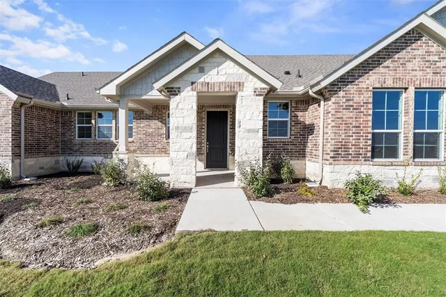 a front view of a house with a yard and potted plants