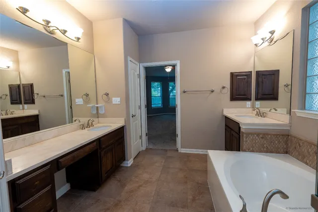 a spacious bathroom with a sink double vanity granite tub shower and a mirror