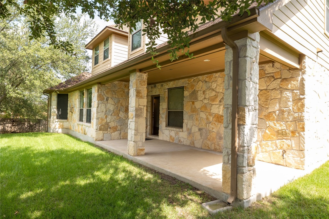 104 Palisades Cove Austin, TX 78732 - Photo 26 of 27 Back of house with stone siding, a yard, and a patio area