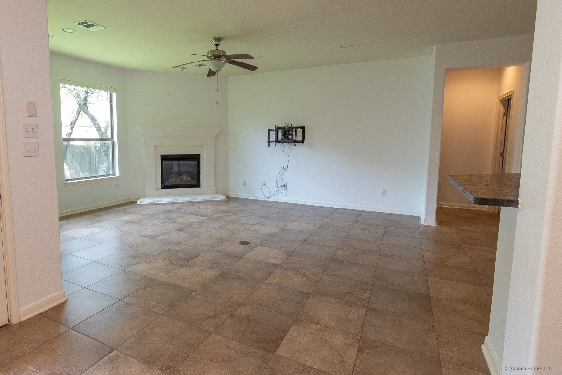 104 Palisades Cove Austin, TX 78732 - Photo 7 of 27 Unfurnished living room featuring a glass covered fireplace and a ceiling fan