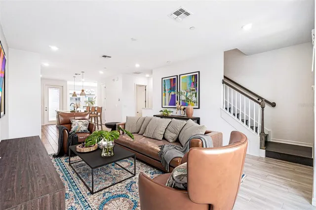 a living room with furniture kitchen view and a wooden floor