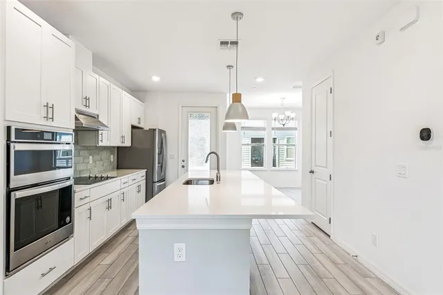 a kitchen with stainless steel appliances a stove a sink a refrigerator a center island and cabinets