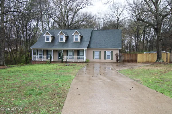 a front view of a house with a garden and trees