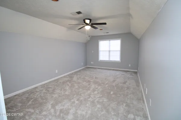 an empty room with a window and ceiling fan