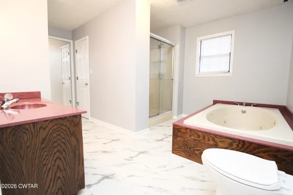 a bathroom with a sink vanity mirror bathtub and window